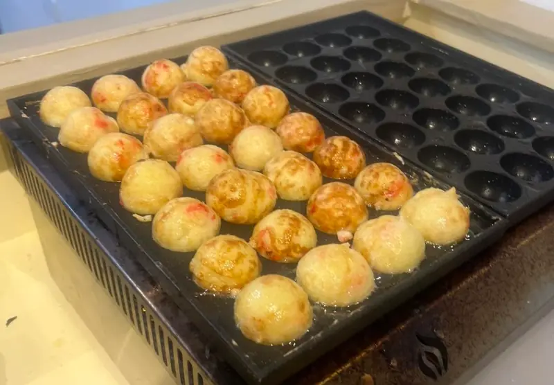 A griddle full of golden takoyaki balls