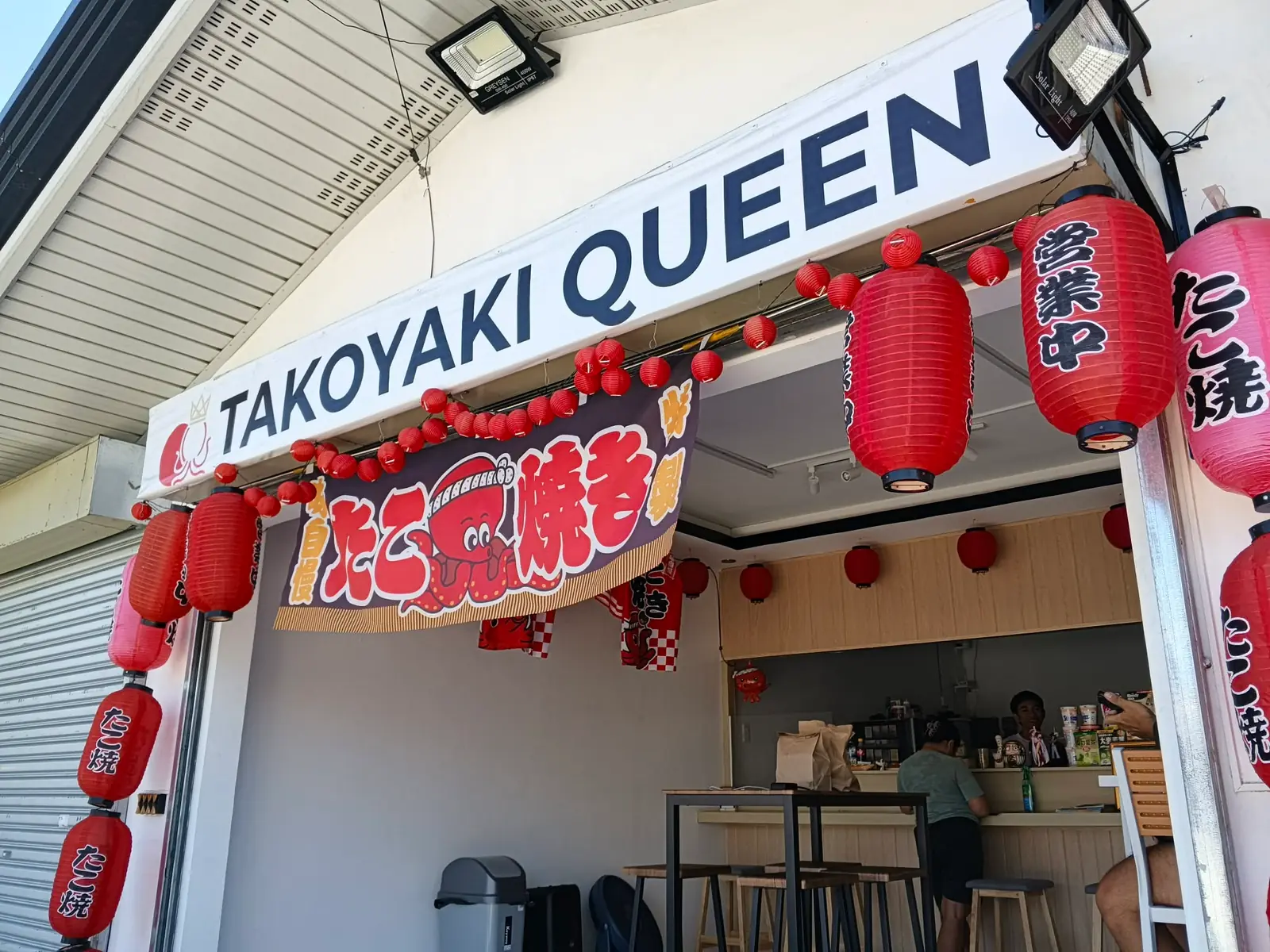 The Takoyaki Queen stall front with its sign, red paper lanterns and a takoyaki banner